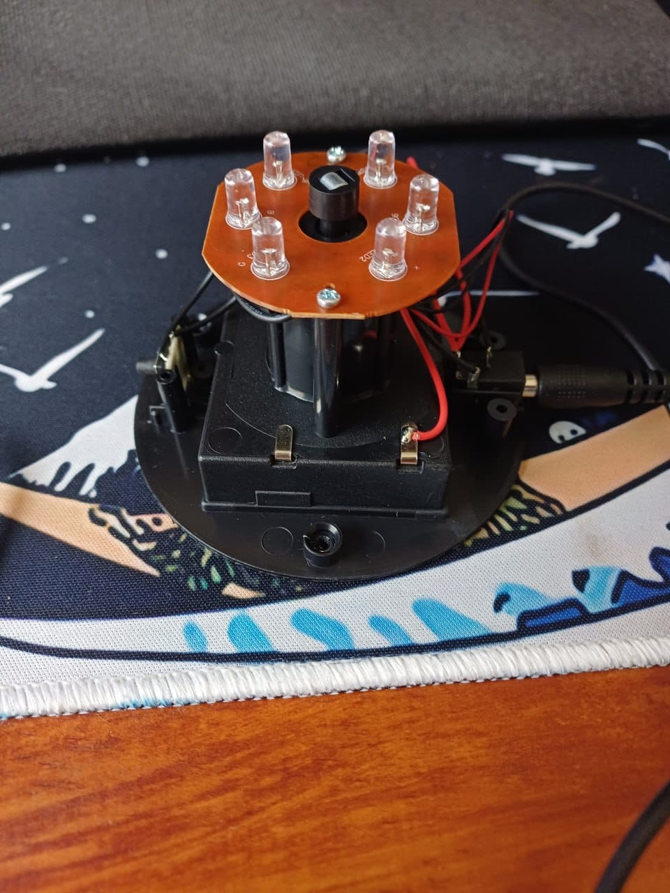 Opened lamp base held in hand, showing the LED board with six clear LEDs and the motor housing