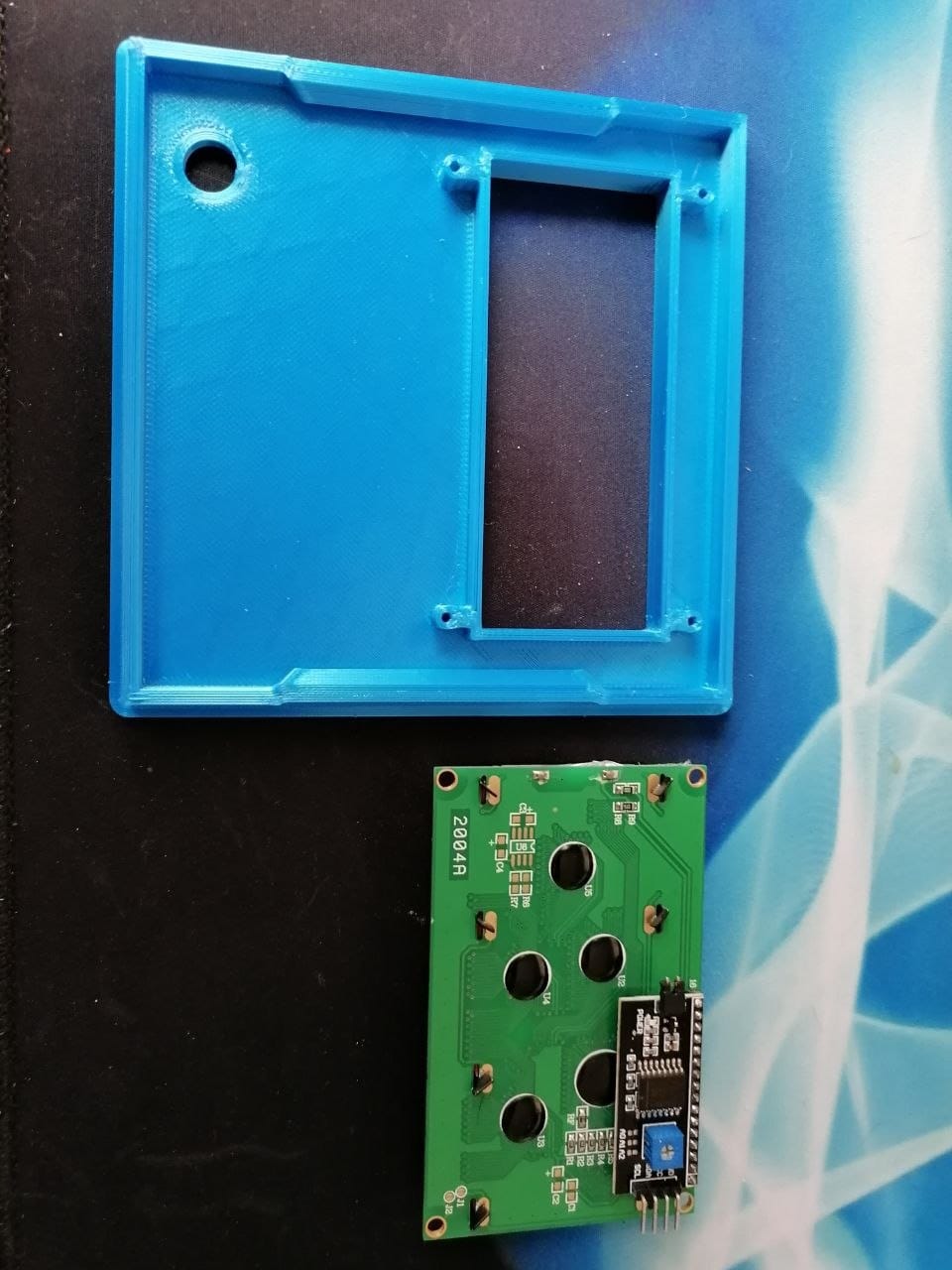 The raw 3D printed front panel next to the green 2004A LCD board that goes behind it