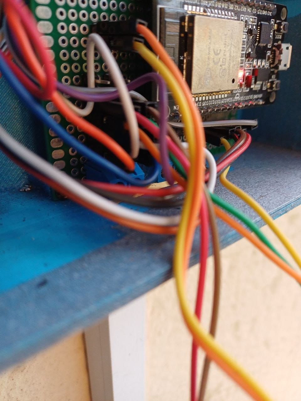 The hand soldered protoboard inside the enclosure, with the blue terminal block for the outgoing wires
