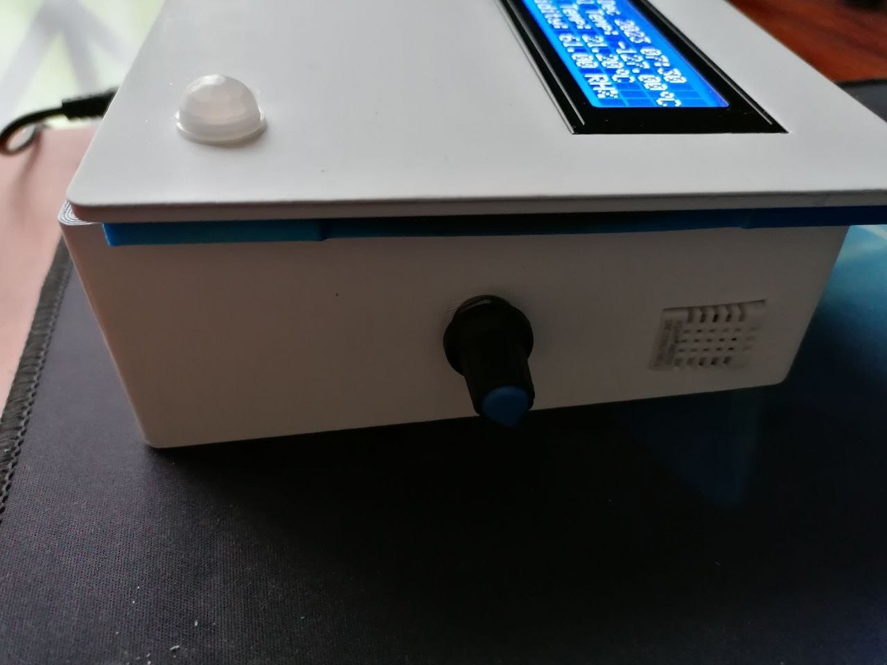 The 3D printed enclosure after being painted white, with the 20x4 LCD showing the statistics menu, the PIR sensor dome on top and the rotary encoder knob on the front