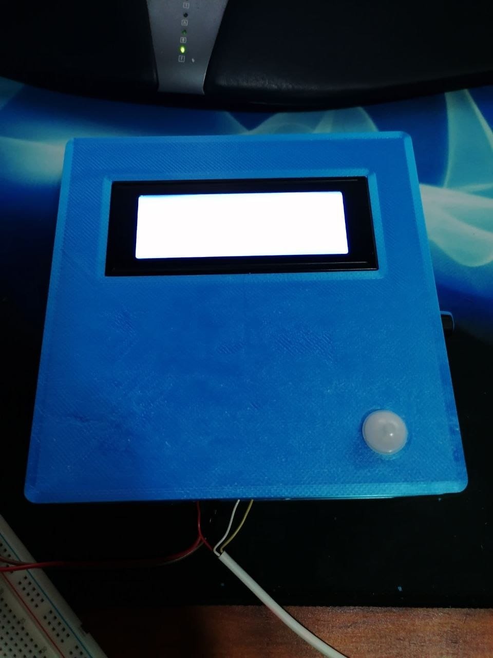 The finished blue 3D printed monitor on the bench with the LCD backlight lit up