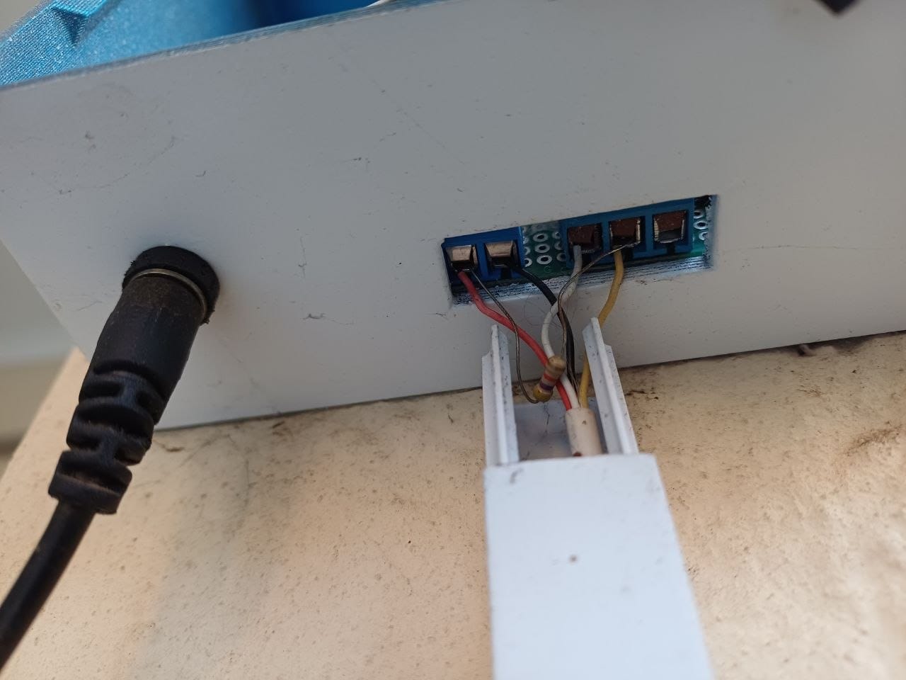 The back of the pool monitor box, showing the four way screw terminal block where the sensor wires leave through white conduit and the power connector beside it
