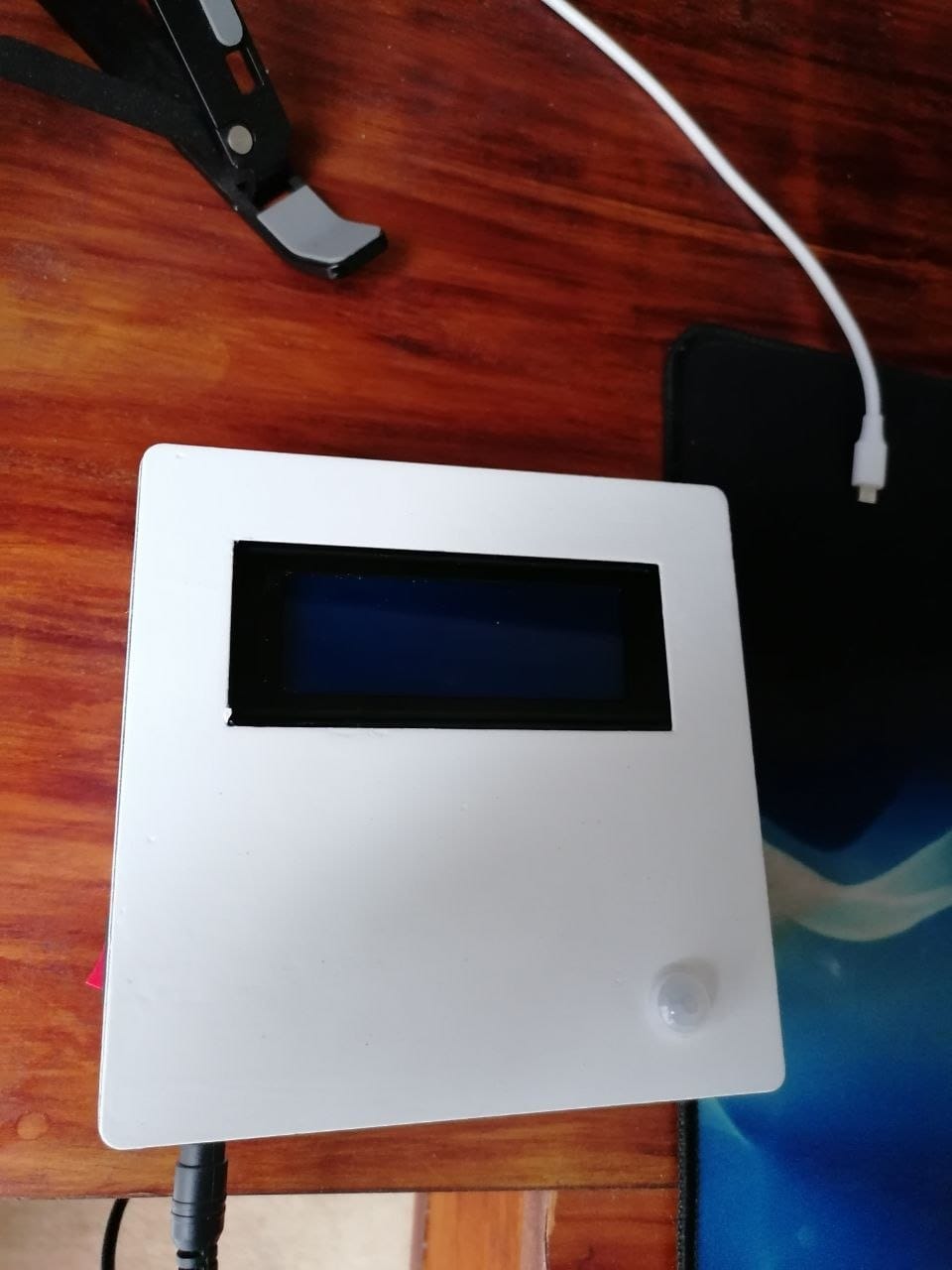 The painted enclosure from above, showing the printed LCD window, the PIR dome and the USB power cable