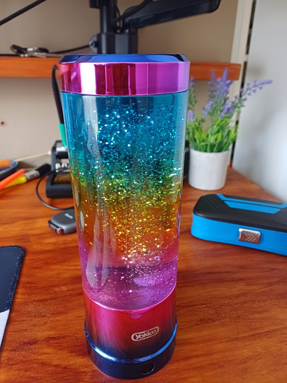 The finished lamp on a wooden desk, lit with a rainbow gradient