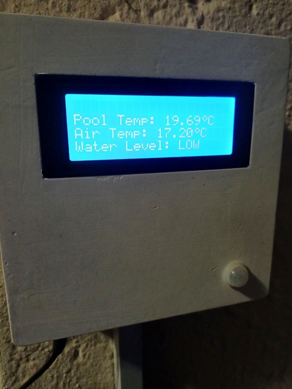 Close up of the wall mounted monitor, its LCD reading Pool Temp 19.69C, Air Temp 17.20C and Water Level LOW