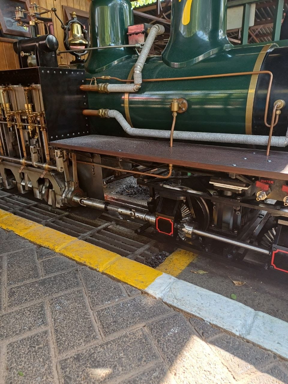 Close-up of a ride-on steam locomotive's boiler with brass bell, copper pipework and polished motion