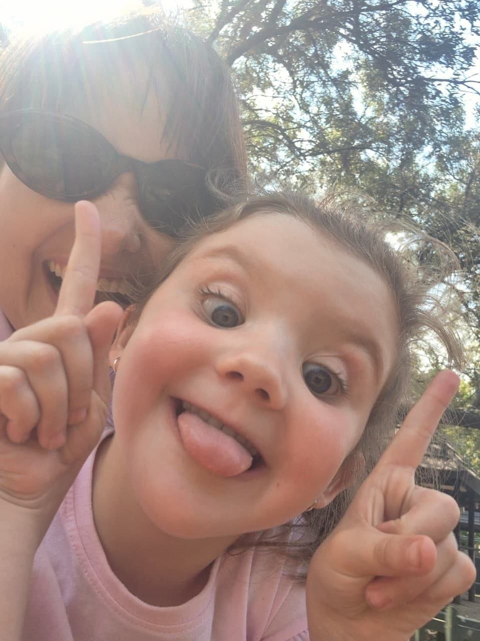 Close-up of Ava pulling a cheeky face with her fists up while Cheryl laughs behind her