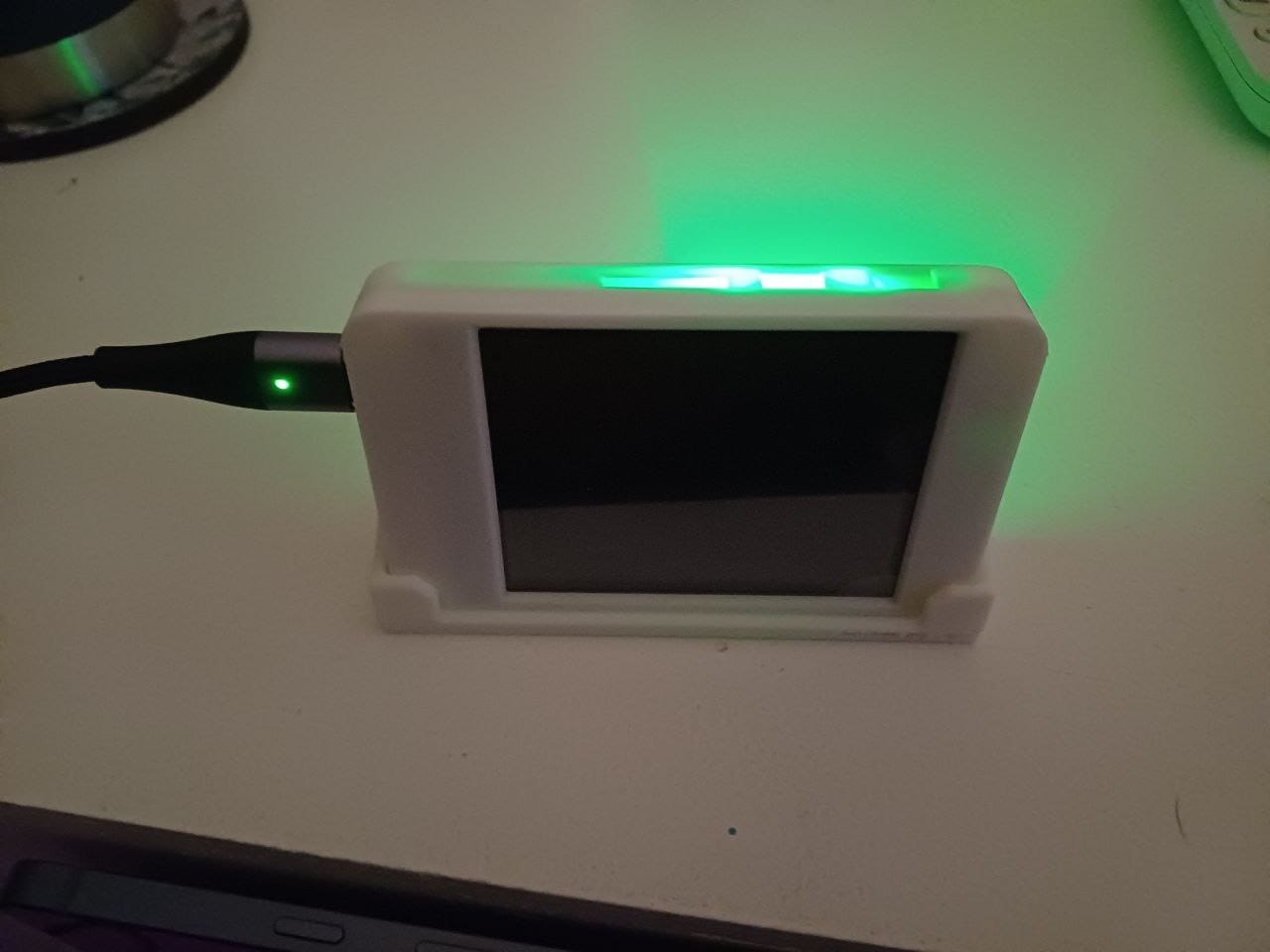 The same bedside display with its screen off and backlight asleep, showing just the white 3D-printed case and the USB cable