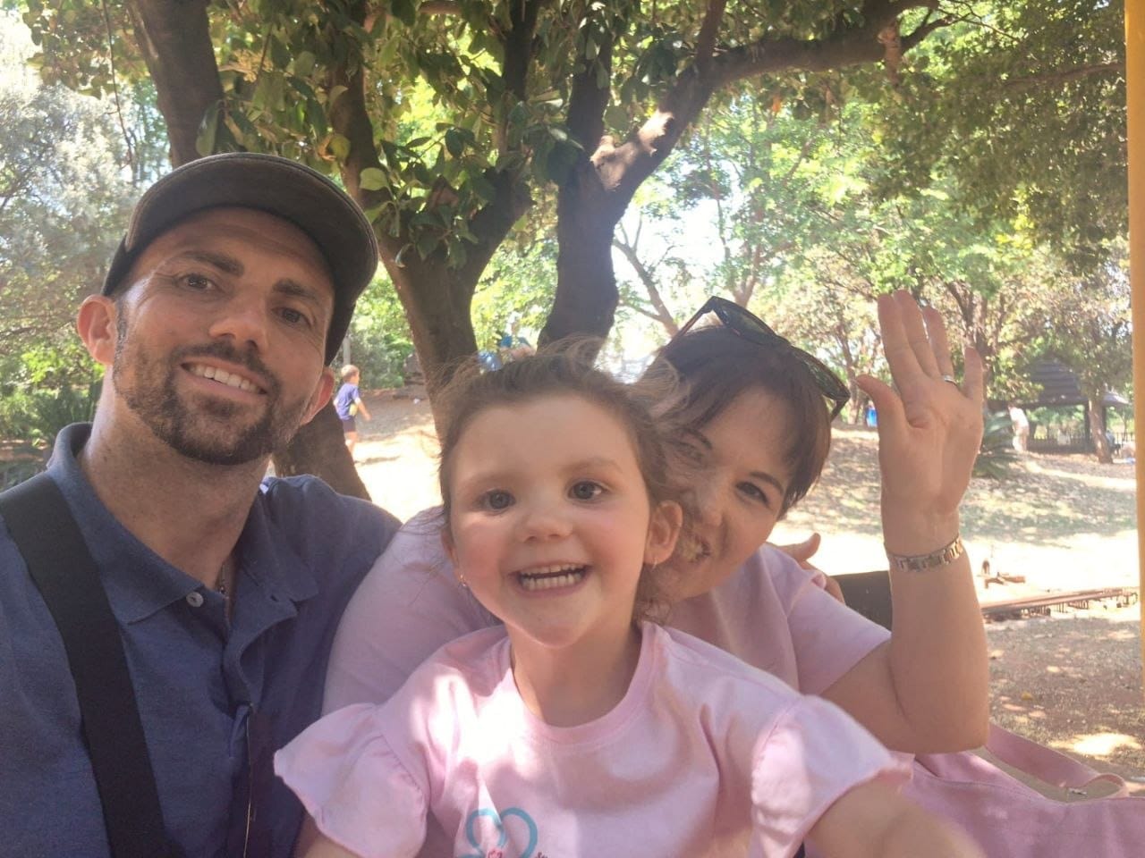 Family selfie under the trees with Cheryl waving at the camera